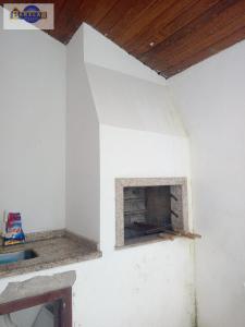 een open haard in een witte kamer met een houten plafond bij Casa 2 dormitórios e garagem. in Florianópolis