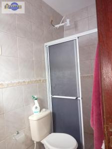 een badkamer met een toilet en een glazen douchedeur bij Casa 2 dormitórios e garagem. in Florianópolis