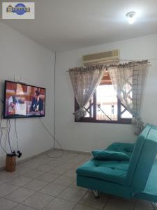 een woonkamer met een blauwe bank en een tv bij Casa 2 dormitórios e garagem. in Florianópolis