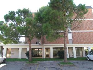 twee bomen voor een bakstenen gebouw bij Appartamento Xibana in Bibione