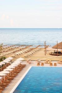 a swimming pool next to a beach with chairs and umbrellas at Sol Tropikal Durrës in Durrës