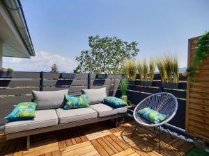 eine Terrasse mit einem Sofa und einem Stuhl in der Unterkunft Détente, confort et sérénité, aux portes de Genève in Collonges