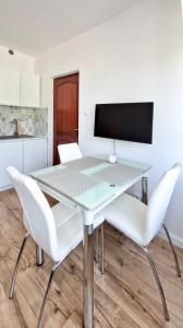 een glazen tafel met twee witte stoelen in een keuken bij Apartamenty Harnaś in Rytro