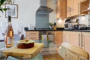 a kitchen with a bottle of wine and a cake on a table at 10 Summerhouse Mews in York +3 photos