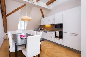 uma cozinha com armários brancos e uma mesa e cadeiras pretas em Wishlist Old Prague Residences - New Town em Praga