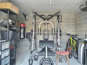 einen Fitnessraum mit einem Stuhl in einem Zimmer mit Fahrrädern in der Unterkunft Détente, confort et sérénité, aux portes de Genève in Collonges