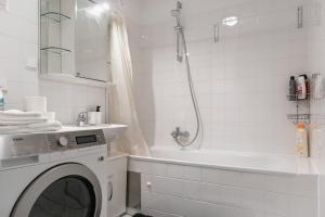 a white bathroom with a washing machine and a tub at Gasometer Apartment - Designer Building with Amazing View in Vienna