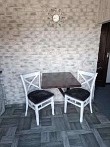 una mesa y dos sillas junto a una pared de ladrillo en Садиба Янчар Номер Студiо з Басейном en Mykulychyn