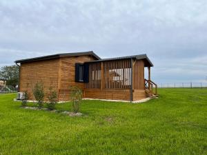 ein kleines Holzgebäude auf einem Grasfeld in der Unterkunft Chalet avec spa, Au Bois Quartois in La Quarte