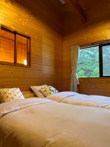two beds in a wooden room with a window at FLYING HOUSE in Chikuni
