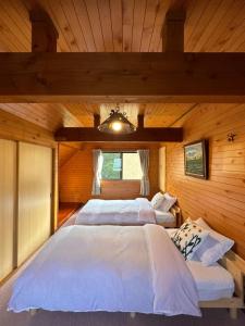 two beds in a room with wooden walls at FLYING HOUSE in Chikuni