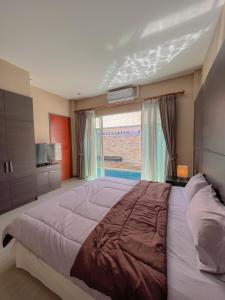 ジョムティエンビーチにあるFeel Like Home Pool Villa Pattayaのベッドルーム1室(大きなベッド1台、大きな窓付)