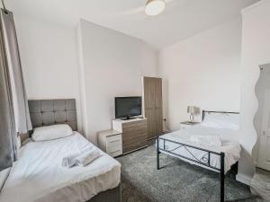 a bedroom with two beds and a tv on a dresser at Bentley House - By Sigma Stays in Crewe