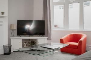 a living room with a red chair and a television at Bentley House - By Sigma Stays in Crewe