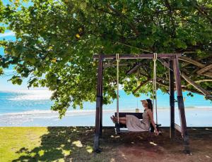 a woman sitting on a swing at the beach at Kacha Resort & Spa, Koh Chang in Ko Chang