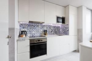 una cucina con armadi bianchi e forno nero di Lisbon Central Apartment with Balcony a Lisbona