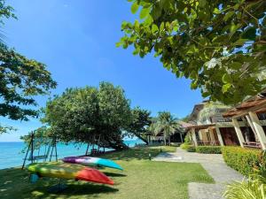 a group of boats sitting on the grass near the water at Kacha Resort & Spa, Koh Chang in Ko Chang