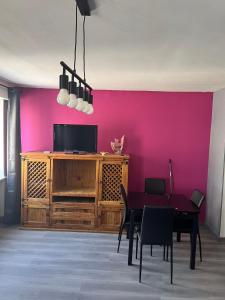a dining room with a table and a pink wall at Studio 50 m de la plage 100 m centre ville in Berck-sur-Mer