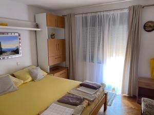 a bedroom with a large yellow bed and a window at Guesthouse Šimag in Rab