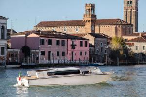 a white boat in the water in front of buildings at Hyatt Centric Murano Venice in Murano