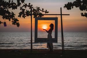 a woman standing in front of a picture of the sunset at Kacha Resort & Spa, Koh Chang in Ko Chang