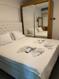 een bed met twee handdoeken en een spiegel bij Avalon otel in Kuşadası