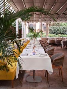 a long white table in a restaurant with chairs and plants at Hyatt Centric Murano Venice in Murano