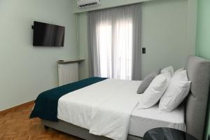 Schlafzimmer mit einem weißen Bett und einem TV in der Unterkunft Konstantina Apartment in Athen