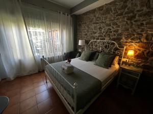 a bedroom with a bed and a stone wall at Hostal Casa San Nicolas in Molinaseca