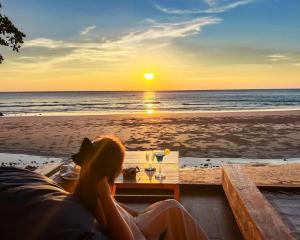 a woman sitting at a table on the beach watching the sunset at Kacha Resort & Spa, Koh Chang in Ko Chang