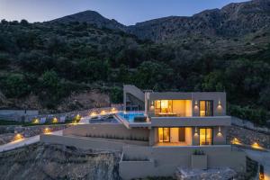 a house on the side of a mountain at night at Epsilon Villa, Private Swimming Pool Garden, Panoramic Sunset in Rethymno Town