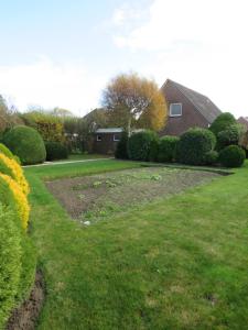 a yard with a garden with bushes and a house at Ferienhaus PH 17 in Krummhörn