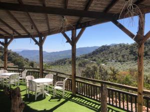 a porch with white chairs and tables and a view of mountains at Villa La Margarita Rocabella in El Chorro