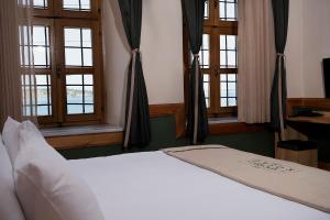 - un lit blanc dans une chambre avec fenêtres dans l'établissement Kocanli Kosku, à Dikili