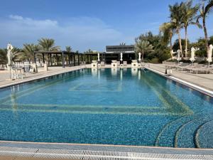 I Like Al Hamra Palace - Elite Beach & Golf Resort Private Suites في رأس الخيمة: مسبح ازرق كبير مع الكراسي والنخيل