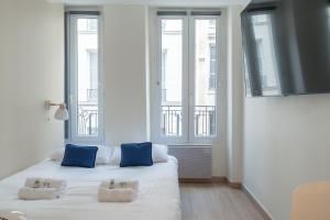 dwa łóżka w pokoju z dwoma oknami w obiekcie Lavie Maison Paris AC Retreat w Paryżu