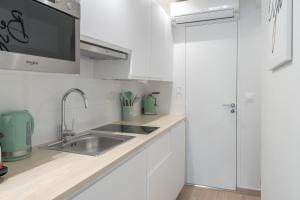 kuchnia z białymi szafkami i zlewem w obiekcie Lavie Maison Paris AC Retreat w Paryżu