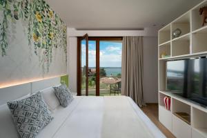 a bedroom with a white bed and a large window at Olivi Hotel & Natural Spa in Sirmione