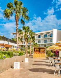 un hôtel avec des palmiers, des tables et des chaises dans l'établissement Hyatt Place Taghazout Bay, à Taghazout