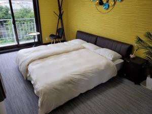 1 cama grande en un dormitorio con pared amarilla en クエーキーセンス琵琶湖 quakysense biwako villa for 4 to 8 people and family by Biwako Lake en Kido