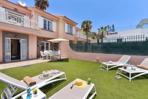 a backyard with a lawn with two chairs and an umbrella at Chalet Santa Ana 24 by VillaGranCanaria in Playa del Ingles
