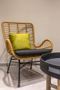una silla de mimbre con una almohada amarilla sentada junto a una mesa en Andrews Luxury Suites Near The Airport, en Heraclión