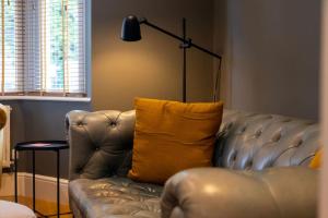 a leather couch with a yellow pillow in a room at Hereford - Clifton Villa - Beautifully Presented House Located A Short Walk From City Centre - Sleeps 6 Guests - Perfect For Exploring Hereford - Hosted By RENTMYHOUSE in Hereford
