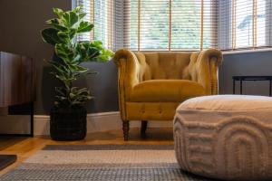 a yellow chair sitting in a living room with plants at Clifton Villa By RentMyHouse in Hereford