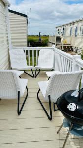 eine Terrasse mit 2 Stühlen, einem Tisch und einem Tisch in der Unterkunft CASALIE at Seasalter Whitstable in Seasalter