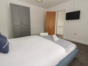 - une chambre avec un grand lit blanc et une télévision à écran plat dans l'établissement Hillside, à Conwy