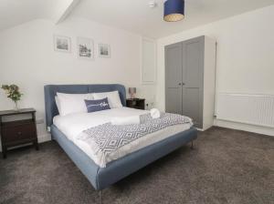 - une chambre avec un lit doté d'une tête de lit bleue et d'une armoire dans l'établissement Hillside, à Conwy
