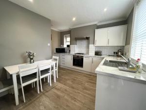 uma cozinha com armários brancos e uma mesa e cadeiras brancas em Woodside Road, Southbourne em Bournemouth