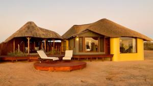 a couple of huts with chairs and tables in front at Kalahari Red Dunes Lodge in Kalkrand