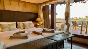 two beds in a room with a balcony at Kalahari Red Dunes Lodge in Kalkrand
